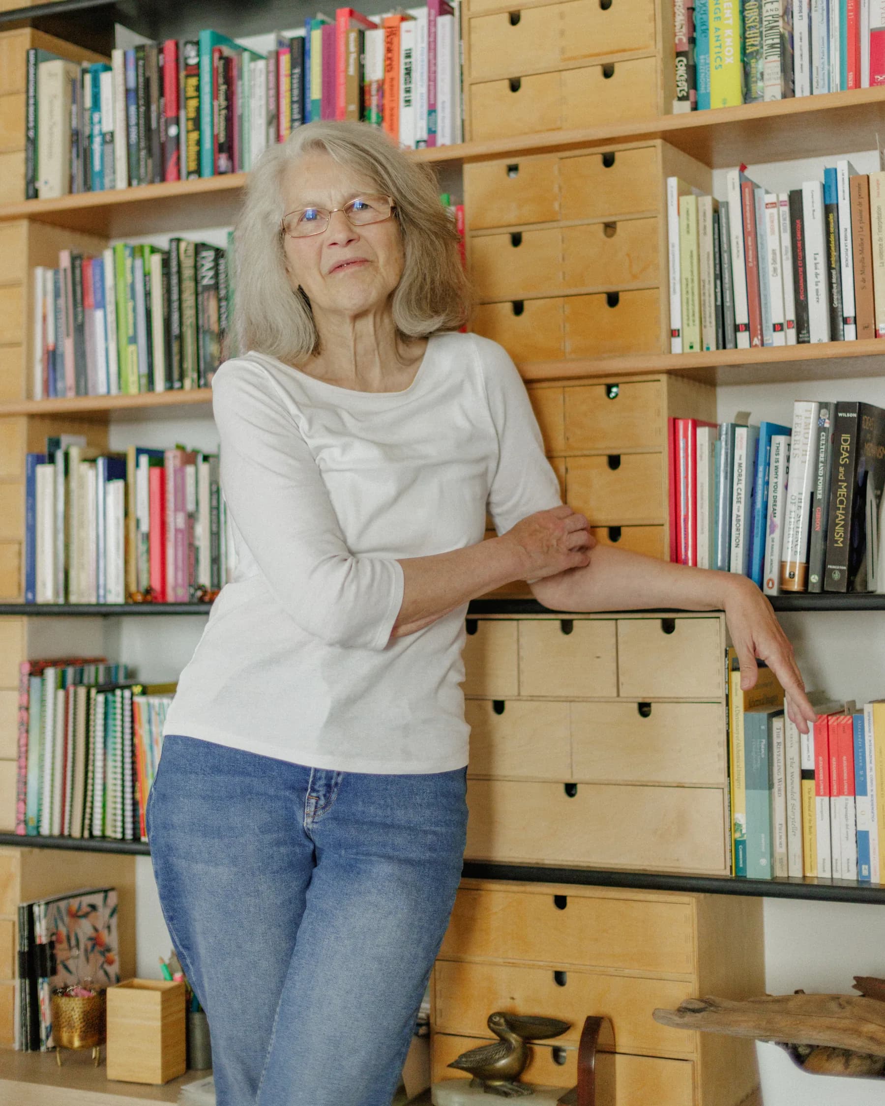 Verónica Blumentals de pie junto a su biblioteca de cajones de madera